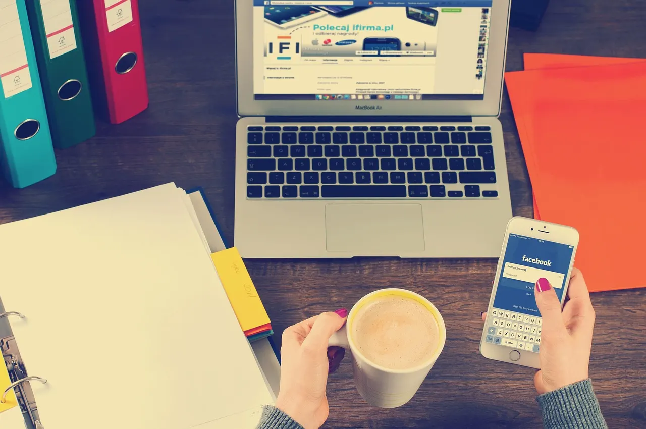 Escritorio con un portátil abierto, carpetas de colores, café y un celular