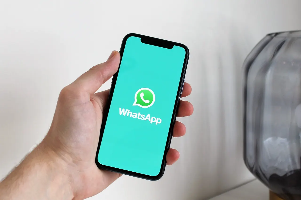Mano sosteniendo un celular con la aplicación de WhatsApp abierta