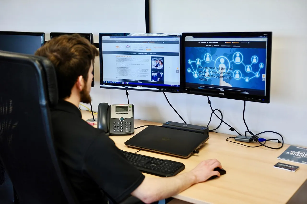 Persona trabajando frente a varios monitores en un escritorio
