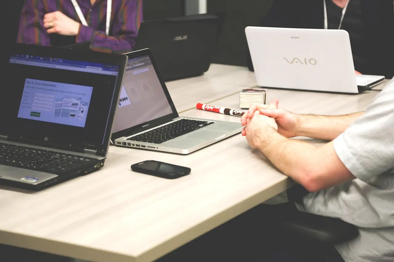 Personas trabajando en portátiles alrededor de una mesa de reuniones