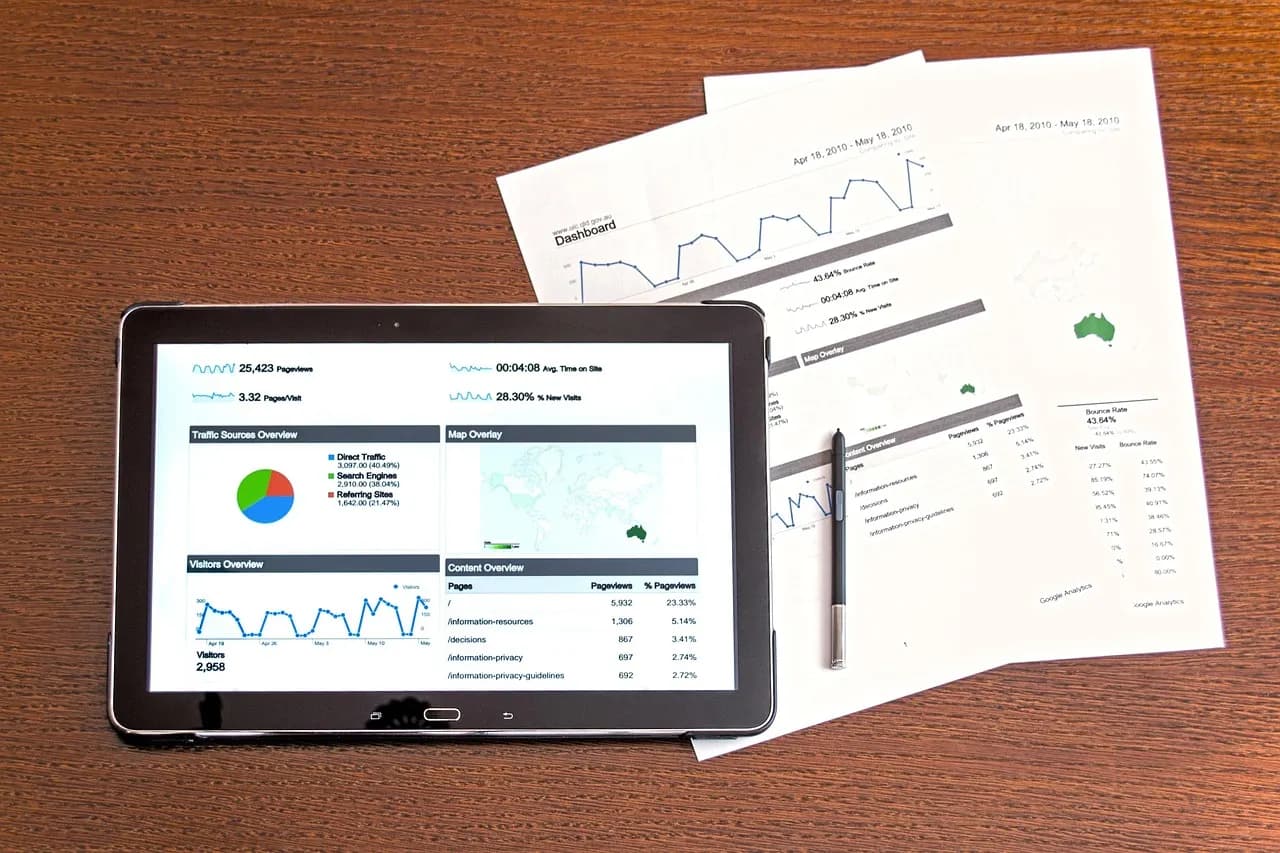 Tableta con reportes de ventas junto a informes impresos