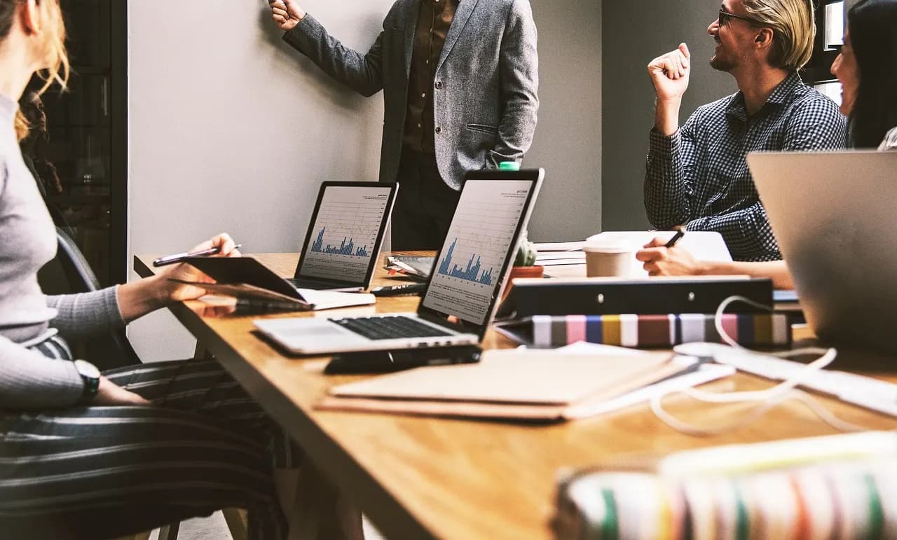 Equipo comercial revisando resultados en portátiles durante una reunión